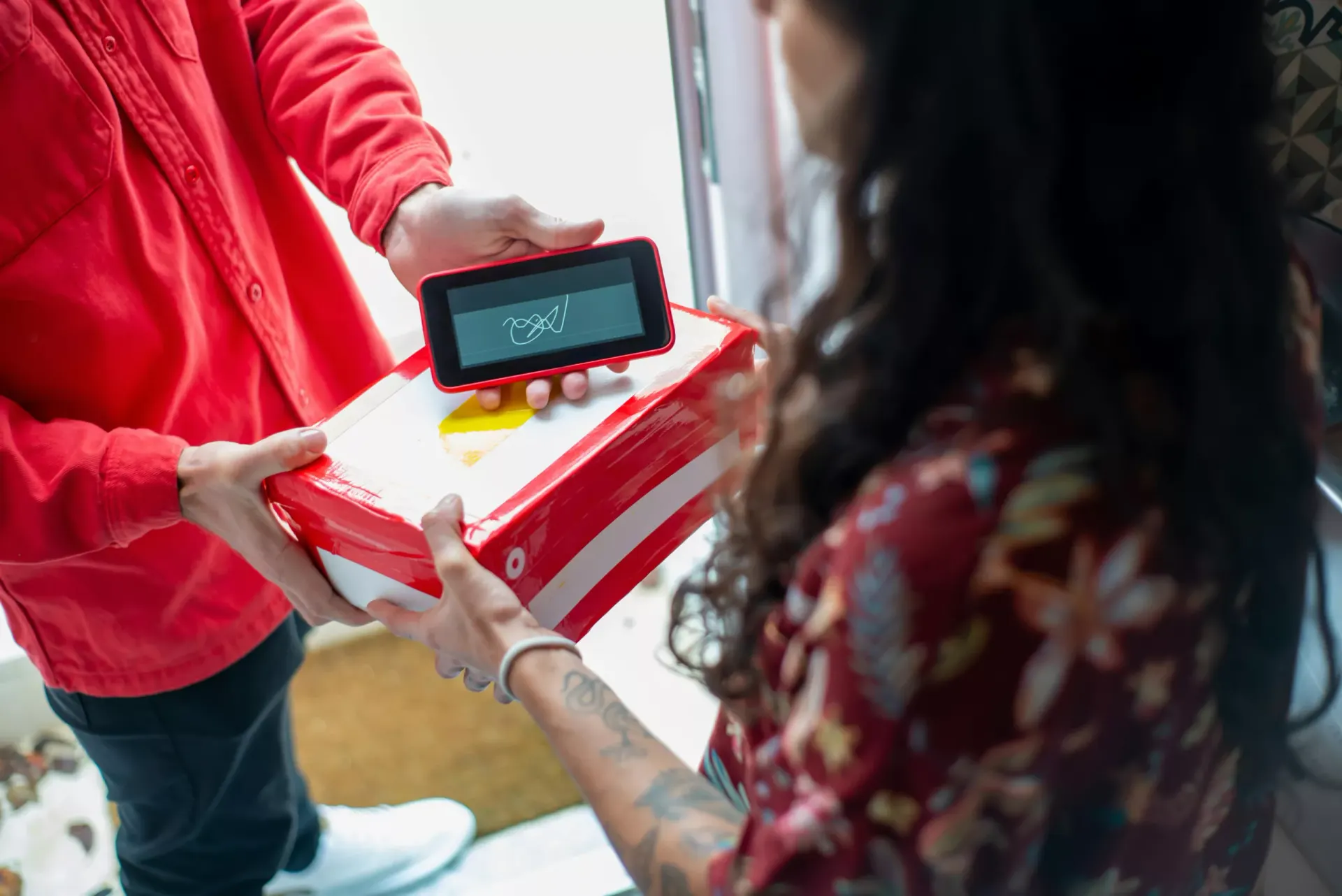 La consegna di un pacco: il corriere porge il tablet per la firma elettronica