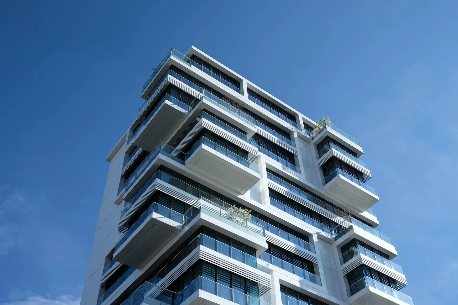 Un condominio moderno a piu' piani con ampi balconi, visto dal basso contro il cielo azzurro